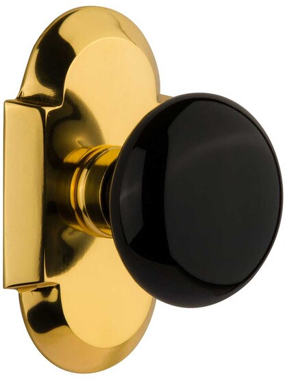 Arched Rosette Door Set with Black Porcelain Knobs in Polished Brass.